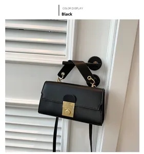 Close-up of black PU leather handbag with golden twist lock on a white shutter door