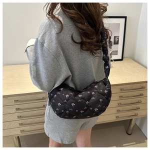 Detail of black quilted cloud bag with pink floral patterns worn as a shoulder bag