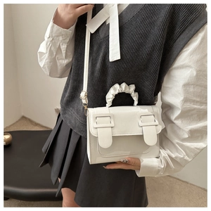 Detail of white crossbody bag with unique cloud-shaped handle and metal buckles