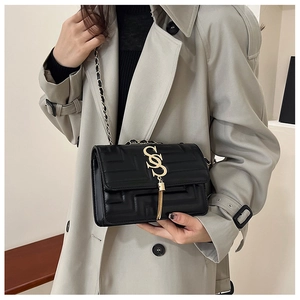 Detail of black quilted leather shoulder bag with gold chain strap and tassel charm