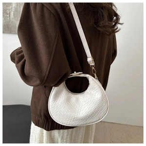 Detail of white crescent bag showing crocodile texture and gold hardware on model