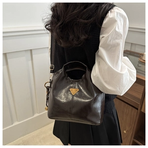Detail of dark brown polished oil wax leather tote bag with gold triangle logo