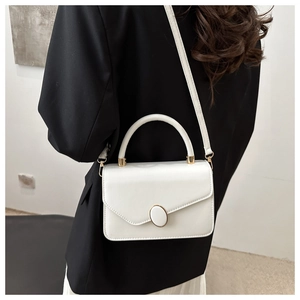 Détail du sac bandoulière blanc avec boucle métallique ovale et poignée élégante
