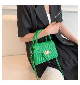 Close-up of bright green quilted handbag with golden square twist lock on a model