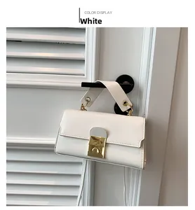 Detailed view of a white leather handbag with a gold square twist lock on a white door
