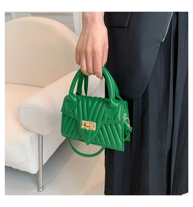 Detail of green quilted handbag with golden twist lock and textured faux leather