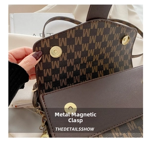 Close-up of golden hardware buckle on a brown leather shoulder bag with M letter print