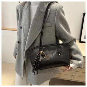 Détail du sac cabas en cuir noir avec pendentifs uniques de clé et raquette de tennis
