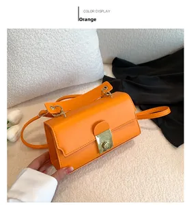Detail view of orange PU leather handbag with gold twist lock on soft plush background