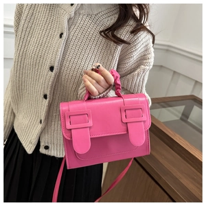 Detail of rose pink handbag with dual decorative buckles and gathered handle texture