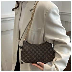 Detail of vintage crescent bag with M-letter monogram pattern and chunky gold chain strap