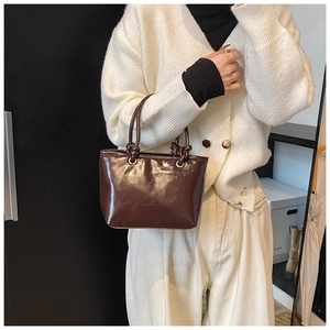 Détail du sac à main en cuir marron brillant avec poignées et nœuds décoratifs