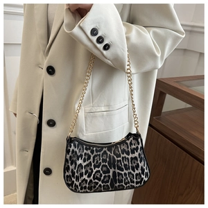Close-up of leopard print hobo bag with gold chain strap worn over a white blazer