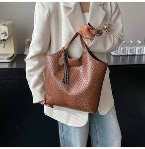 Detailed view of brown woven tote bag with fringe tassel and gold tennis racket charm