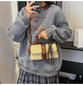 Detail of a beige and brown crossbody bag with tennis racket charm and tassel