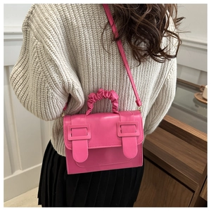 Hot pink crossbody bag with pleated handle and square buckle detail on a model