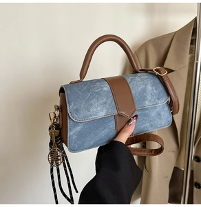 Detail of blue denim and brown leather handbag with tennis racket charm and strap