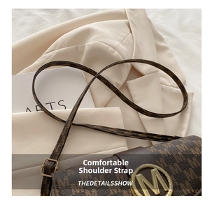 Detail of a brown textured shoulder bag with a gold metal M-logo buckle on a white blazer