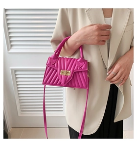Detail of fuchsia mini crossbody bag with V-quilted pattern and gold square turn-lock