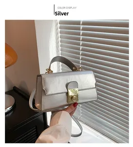 Detail of silver leather handbag with gold lock and textured metallic finish on a table