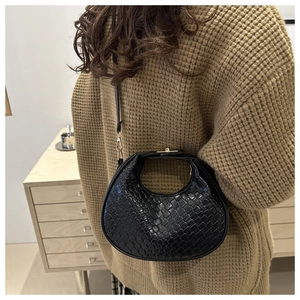 Model wearing black woven hobo crescent bag with polished finish and metal buckle