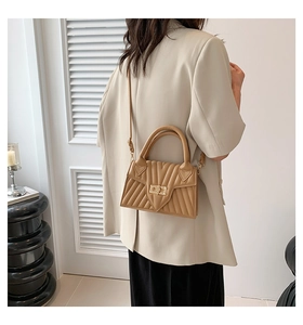 Detail of khaki quilted handbag with gold turn-lock and elegant pleated texture