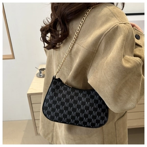 Detail of black monogram hobo bag with gold chain strap on camel suede jacket