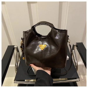 Detailed close-up of dark brown wax leather tote bag with gold triangle hardware
