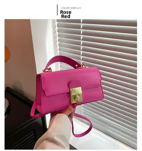 Detail view of rose red handbag with gold square lock and elegant leather texture