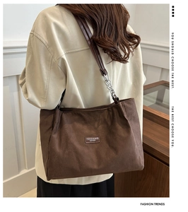 Dettaglio della borsa tote in pelle scamosciata marrone scuro con catena e logo in pelle