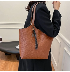 Brown woven texture tote bag with tennis racket charm and stripe detail shown on model