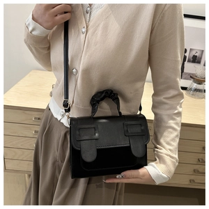Detail of a black textured bag showing the ruched handle and vintage buckle design