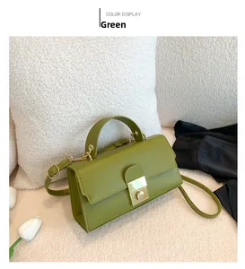 Detail view of olive green crossbody bag with gold square buckle and texture on white pillow