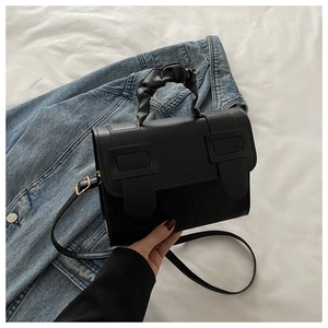 Close-up of black PU leather crossbody bag with buckle detail and ruched handle