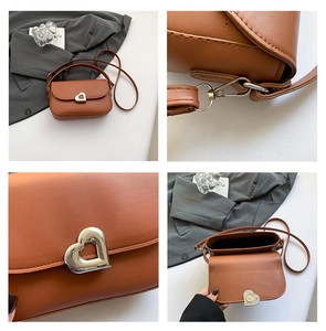 Detail view of caramel leather saddle bag with silver heart metal buckle and fine stitching