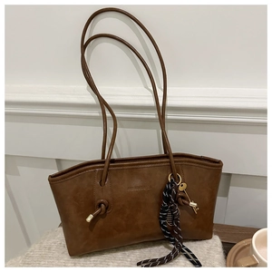Détail d'un sac cabas en similicuir marron avec lanières nouées et accents dorés