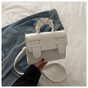 Detail of minimalist white crossbody bag with ruched cloud handle and buckle straps