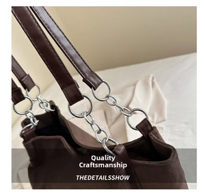 Dettaglio borsa tote in pelle scamosciata marrone con catena argentata e anelli metallici