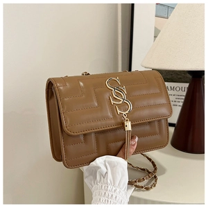 Close-up of brown quilted leather bag with gold logo, fringe detail and chain strap