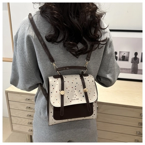 Polka dot backpack with Aimity 1986 logo shown on model in a minimalist room