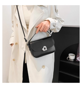 Close-up of black leather handbag featuring a silver heart-shaped metal lock detail
