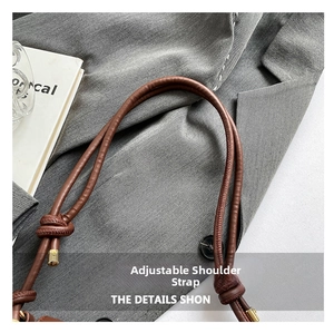 Detail of adjustable round leather strap with gold metal buckle on a brown shoulder bag