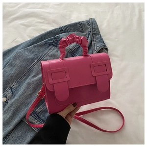 Detail of hot pink crossbody bag with cloud-shaped pleated handle and metal buckles