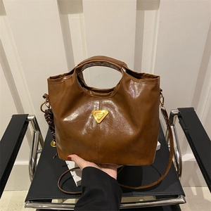 Brown oil wax leather tote bag with a golden triangle plaque and detachable shoulder strap