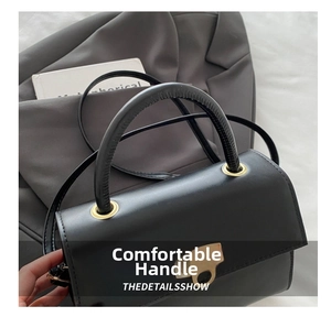 Detail der schwarzen Lederhandtasche mit dickem Griff und goldenem Metallverschluss