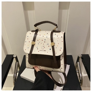 Detail of a minimalist white leather backpack with colorful polka dots and brown accents
