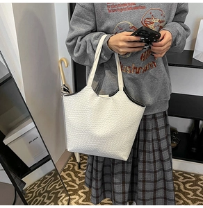 Detail of white woven texture tote bag with black contrast trim on top edge