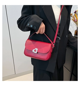Close-up of bright red patent leather handbag featuring a silver heart-shaped metal clasp