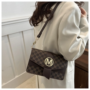 Brown underarm bag with M-letter print and round metal buckle on beige coat