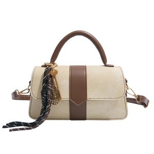 Chic beige canvas handbag with brown leather trim and tennis racket pendant